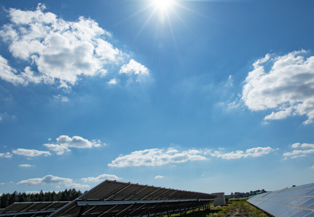 Sun shines in a cloudy sky over solar panels